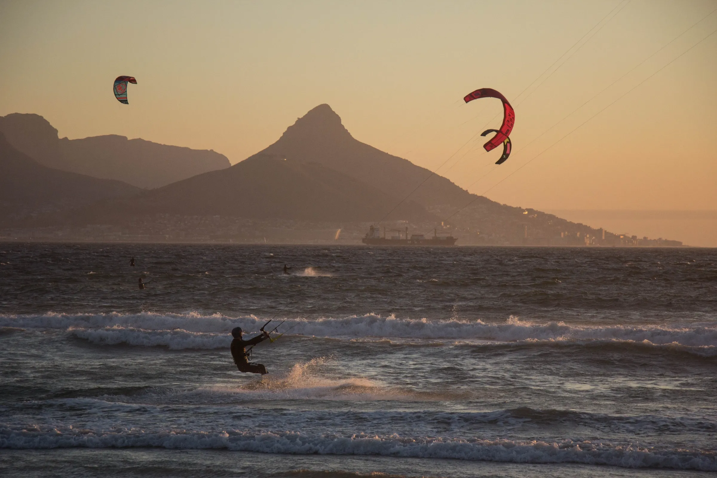 Kitesurfers in the bay at dusk with Table Mountain behind