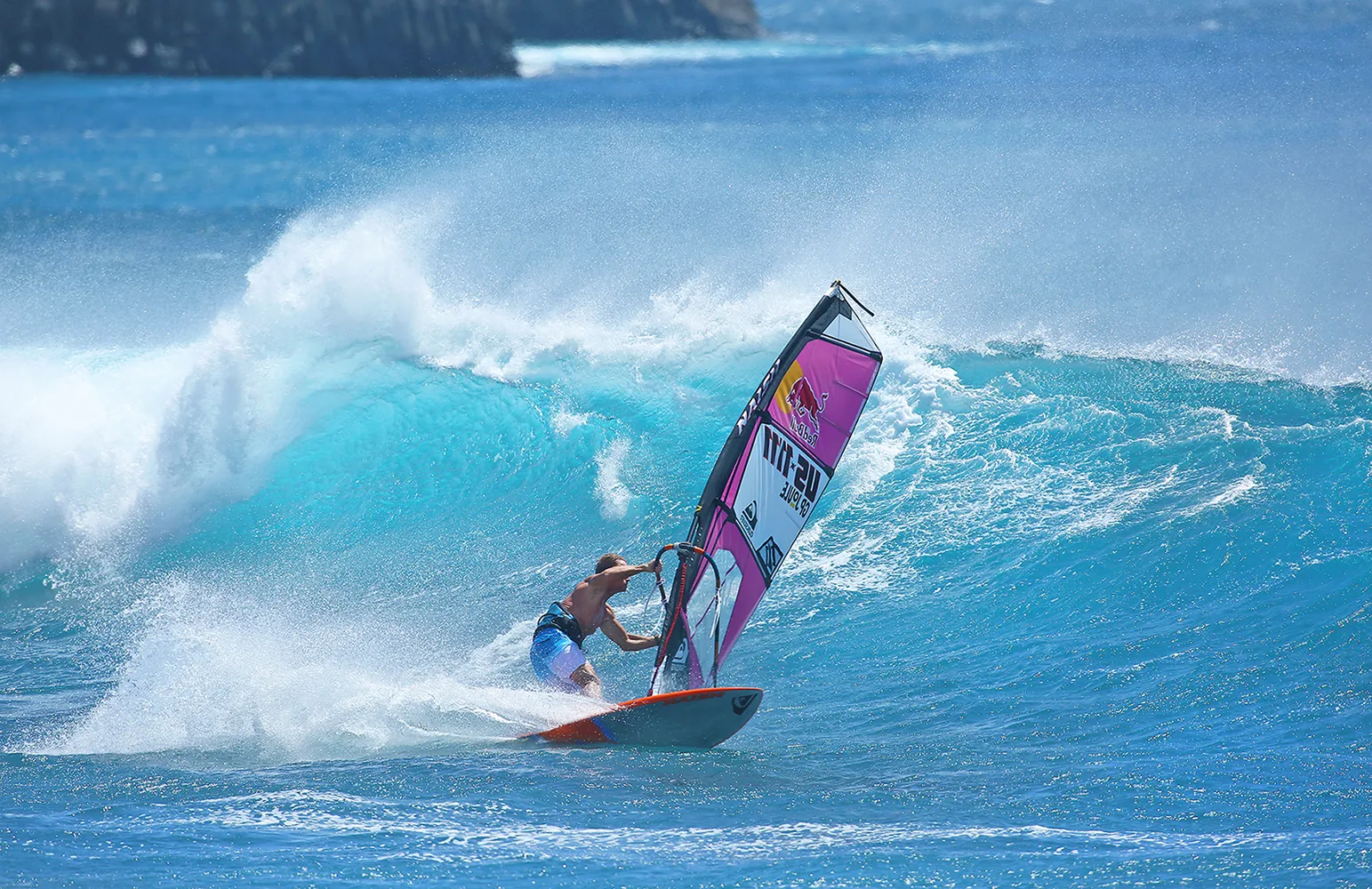 Robby Naish windsurfing, leaning into a turn at the bottom of a wave