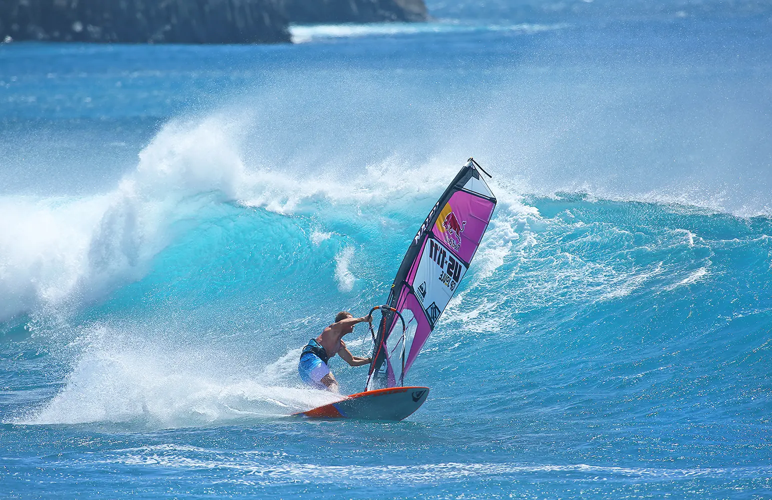 Robby Naish windsurfing, leaning into a turn at the bottom of a wave