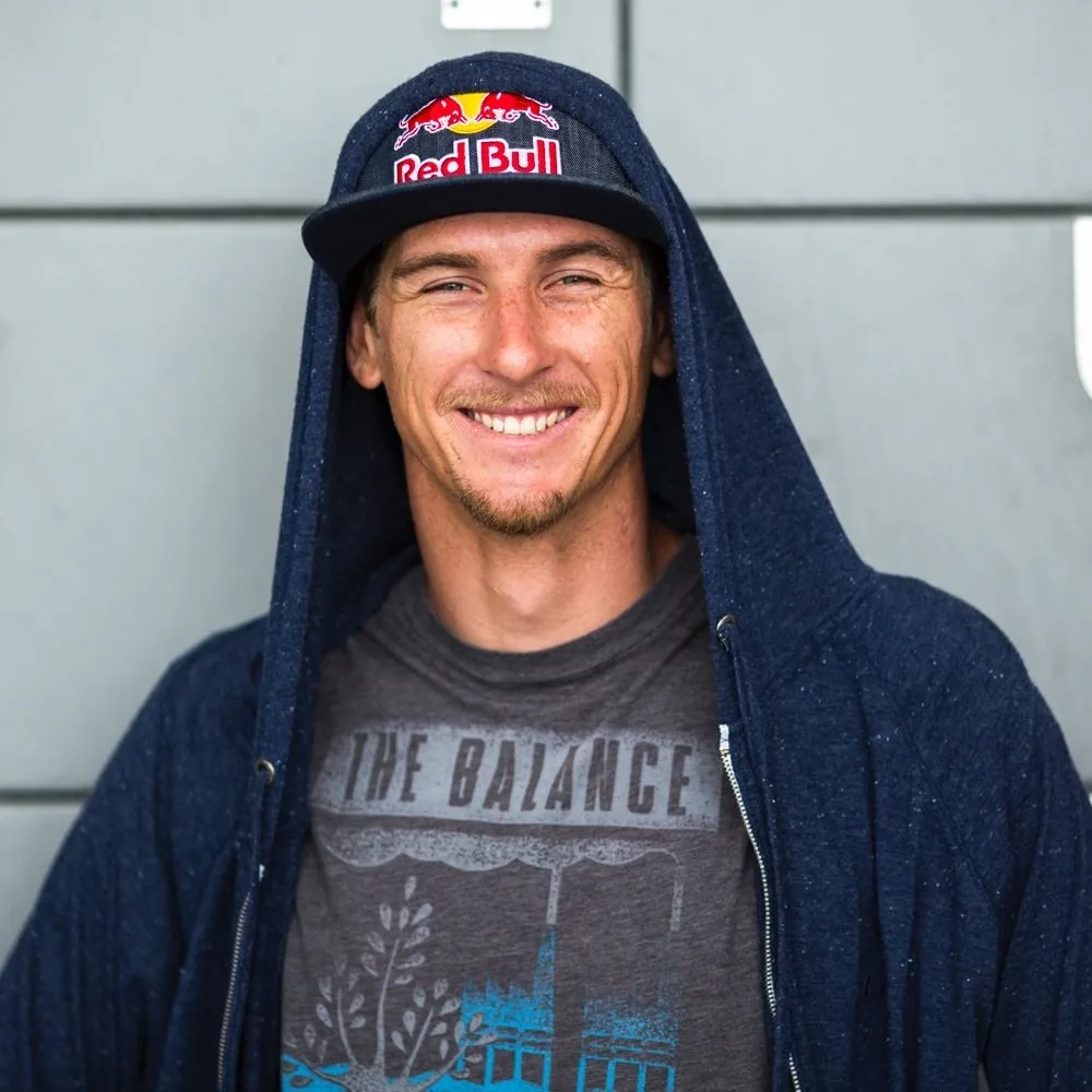 Aaron Hadlow in a cap and hooded jacket, smiling