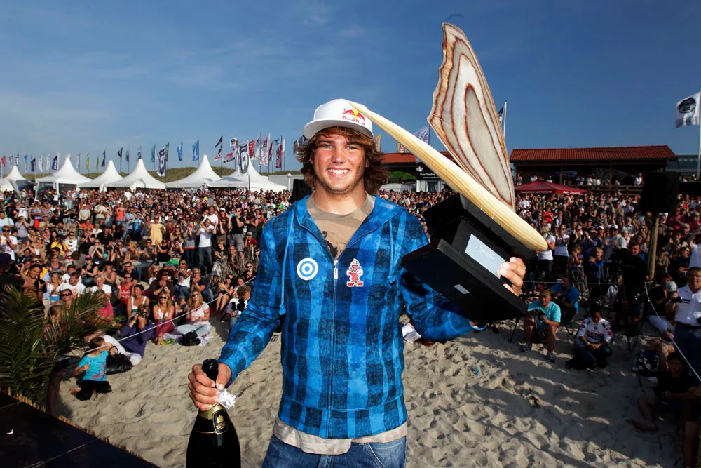Philip Köster in a blue shirt, smiling, in front of a crowd on the beach