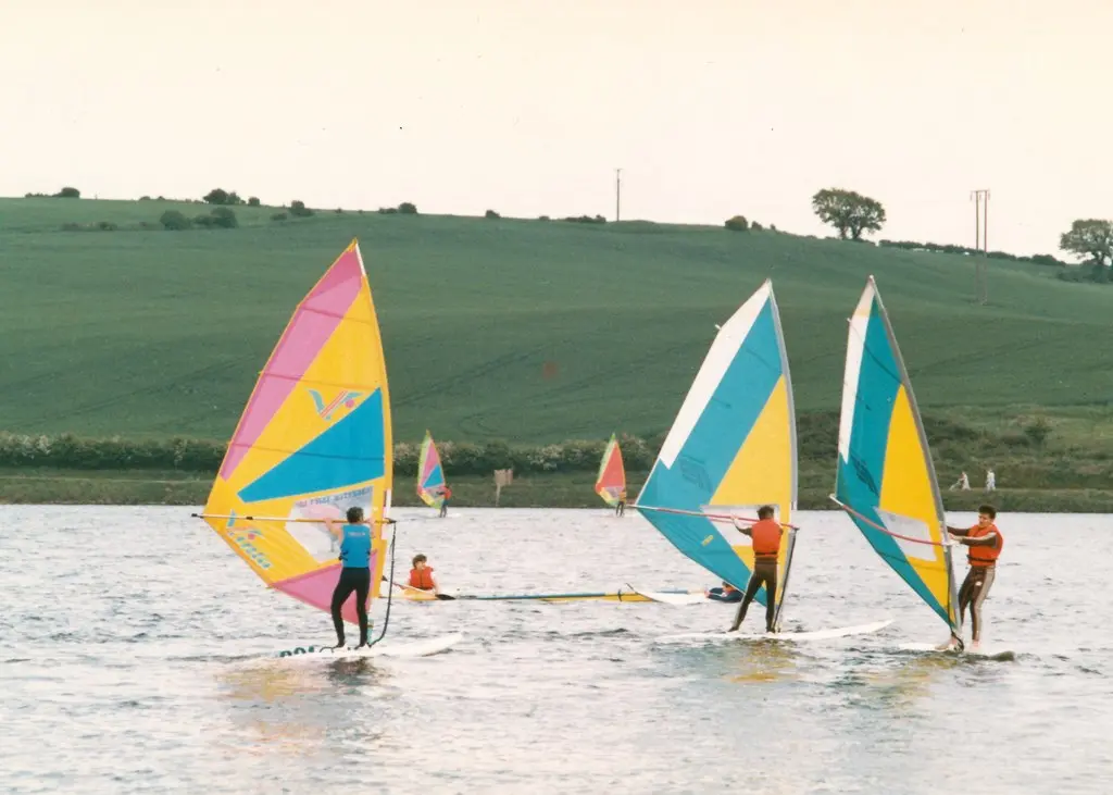Windsurfers with colourful sails on a lake