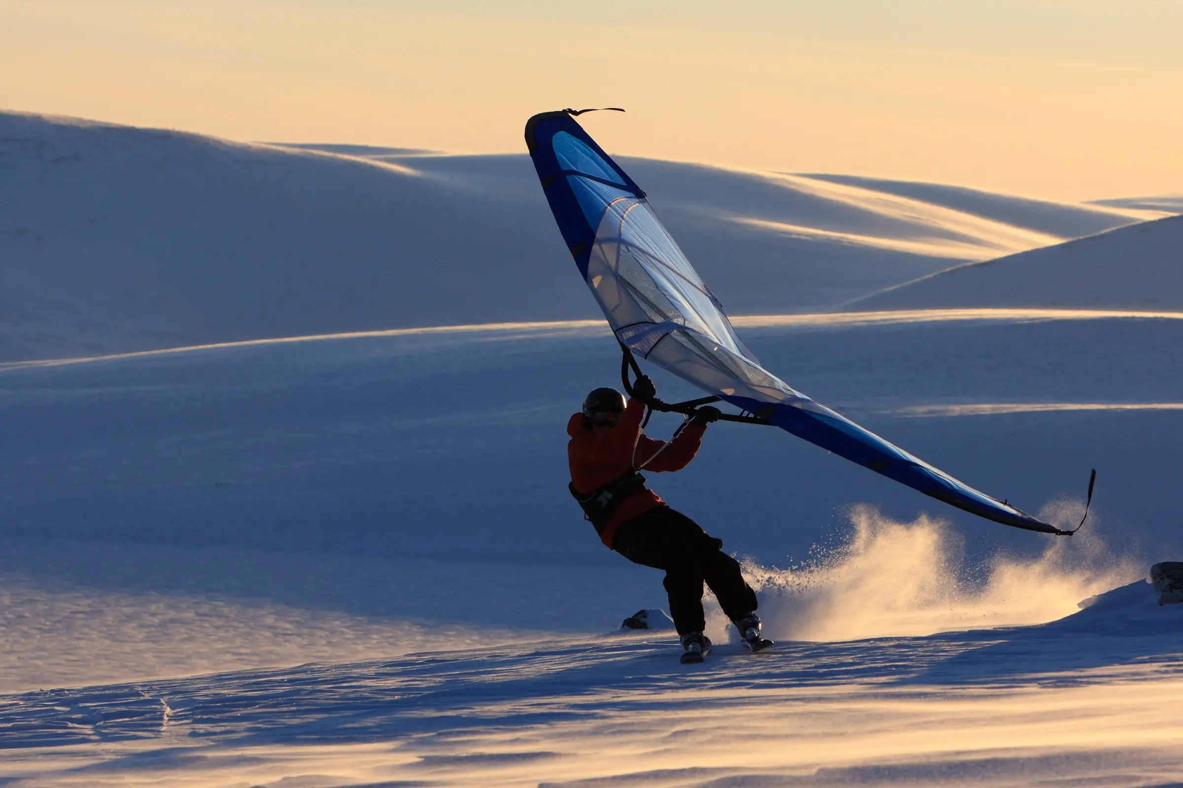 A rider on snow holding a large hand-held wing