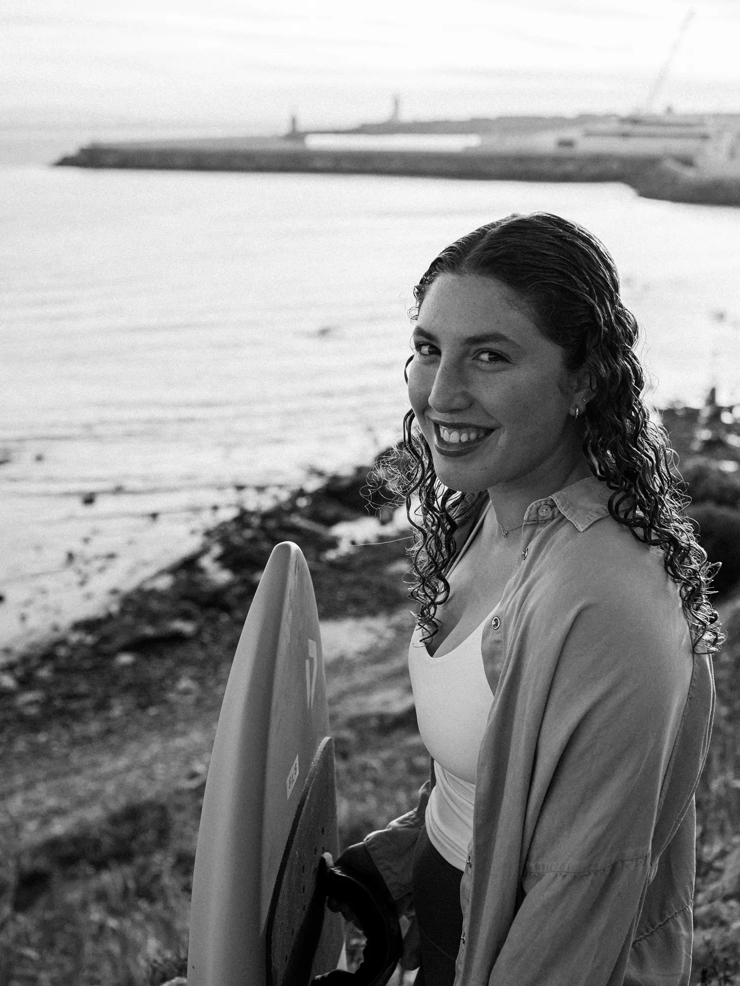 Black-and-white portrait of Nia Suardiaz holding her board
