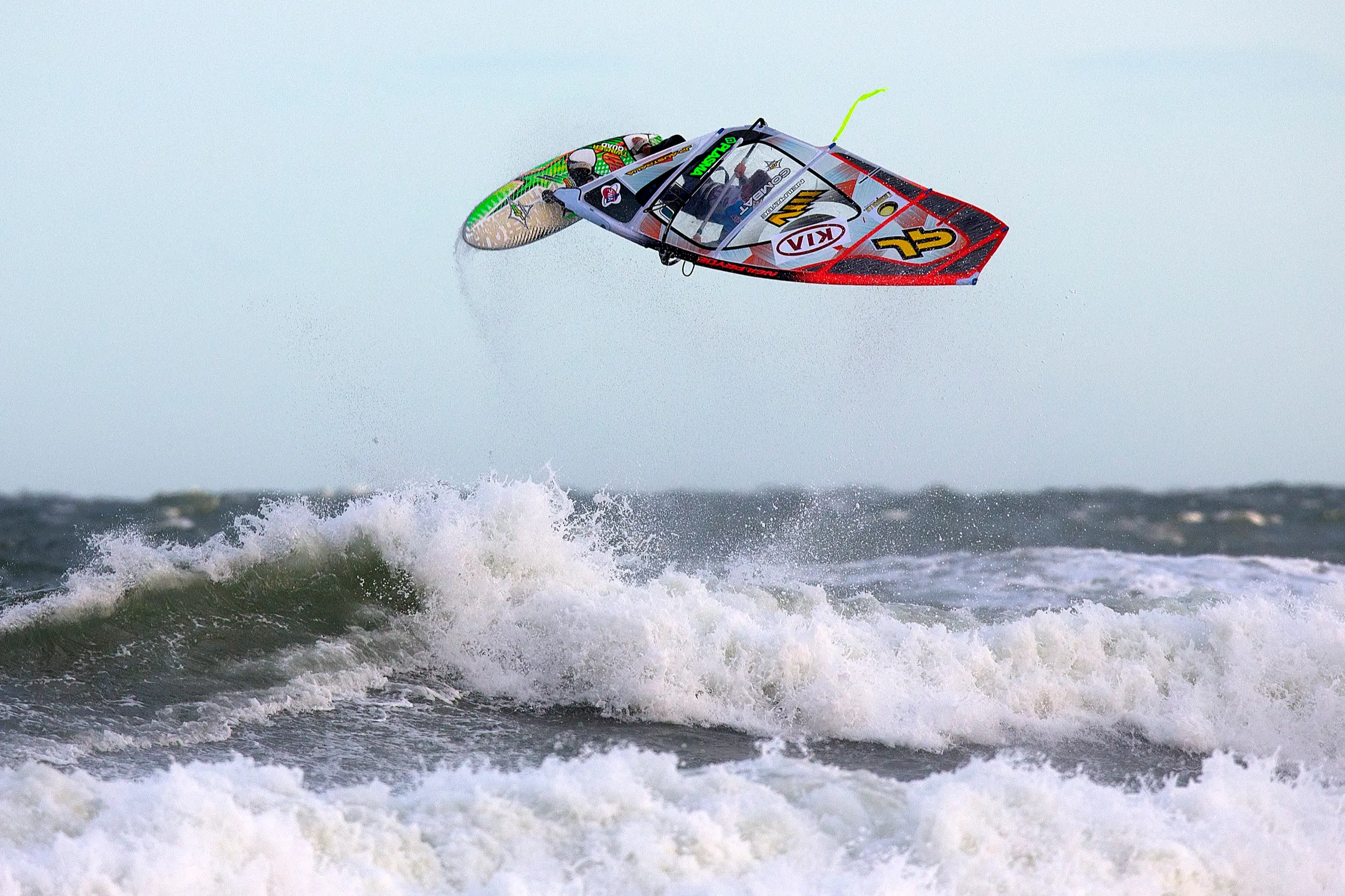 A windsurfer and his rig high in the air above breaking waves