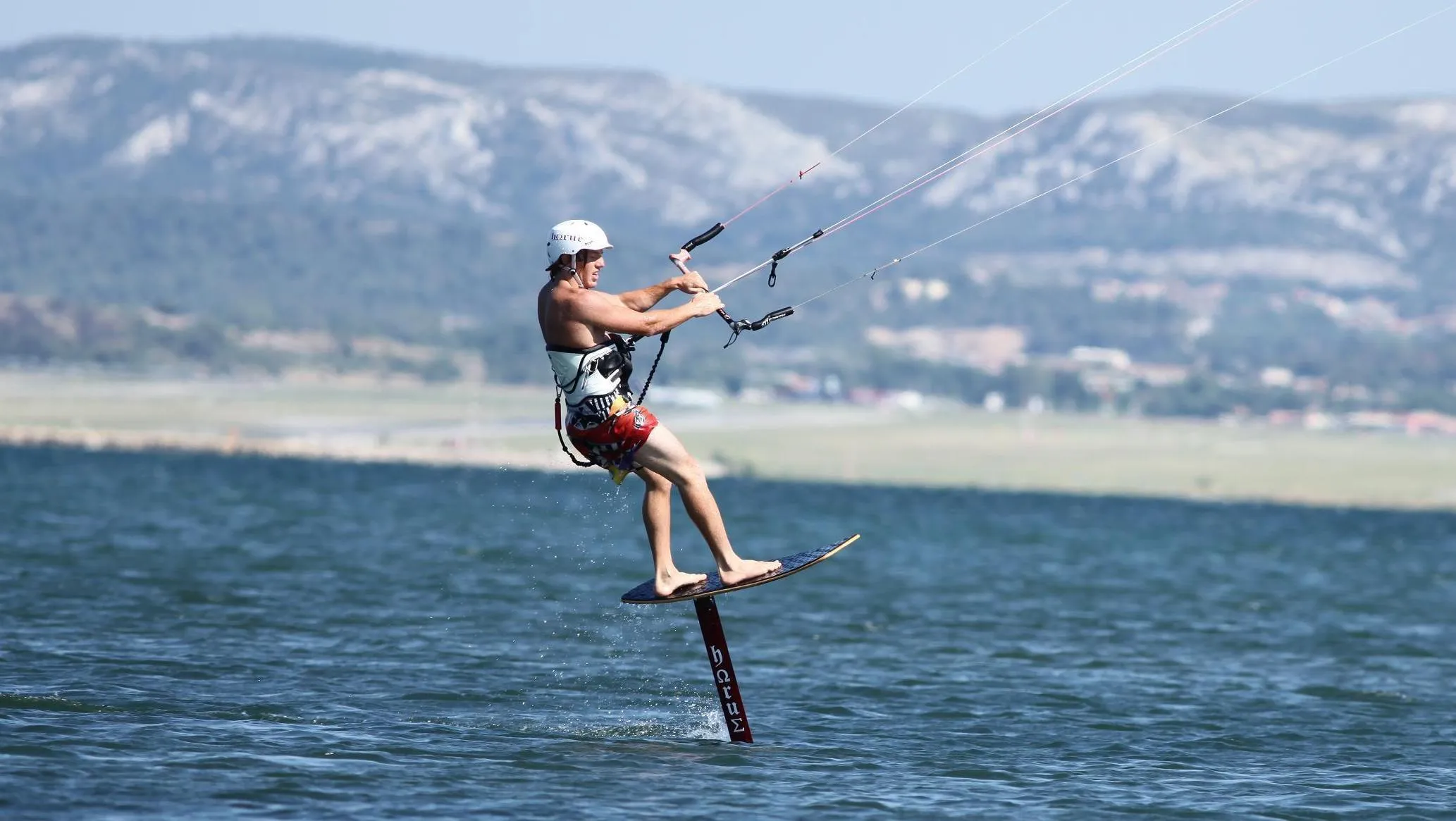 A kitesurfer riding a hydrofoil board above the water