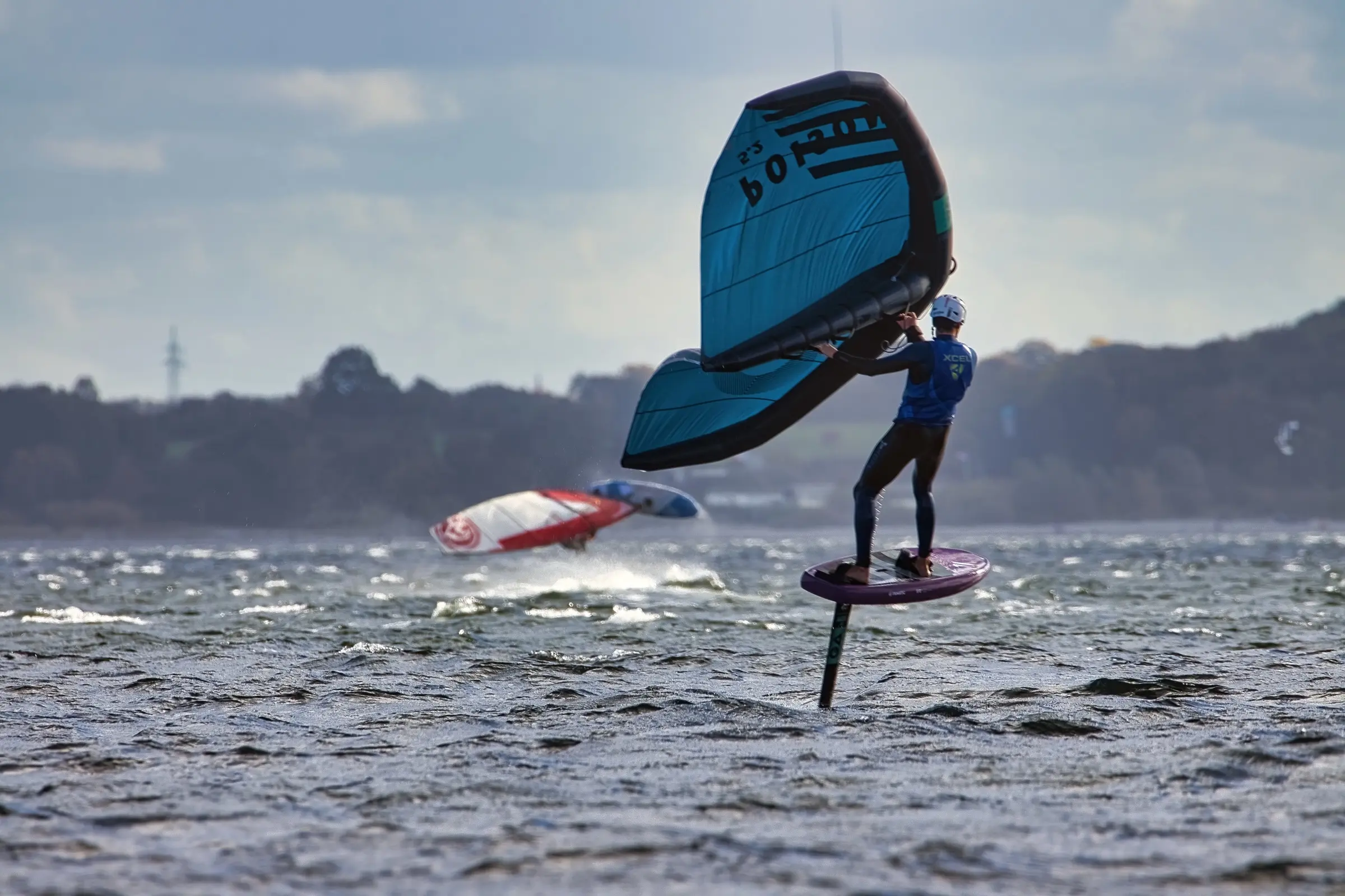 A wing foiler flying above the water of the Kiel fjord