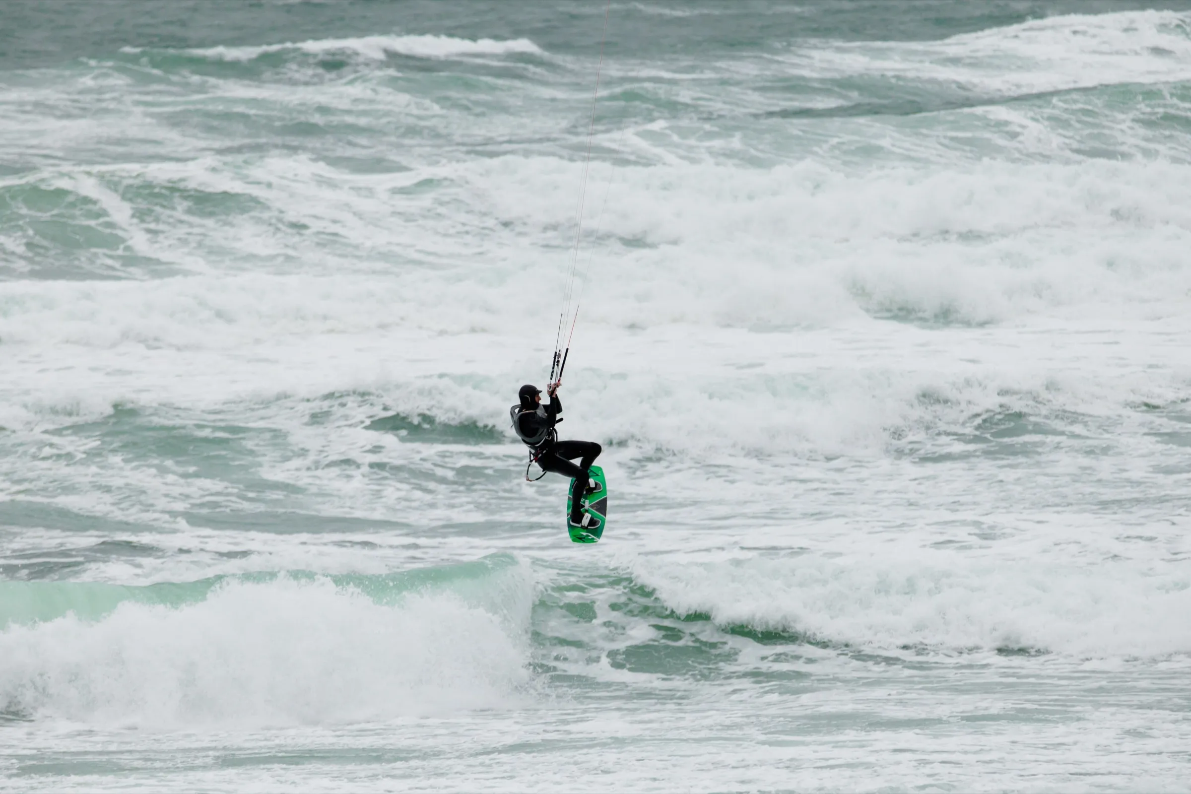 A kitesurfer in the air above ocean waves