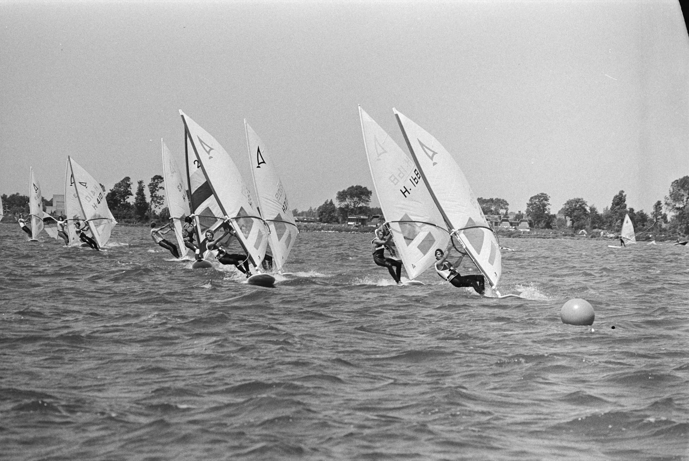 A group of windsurfers racing close together