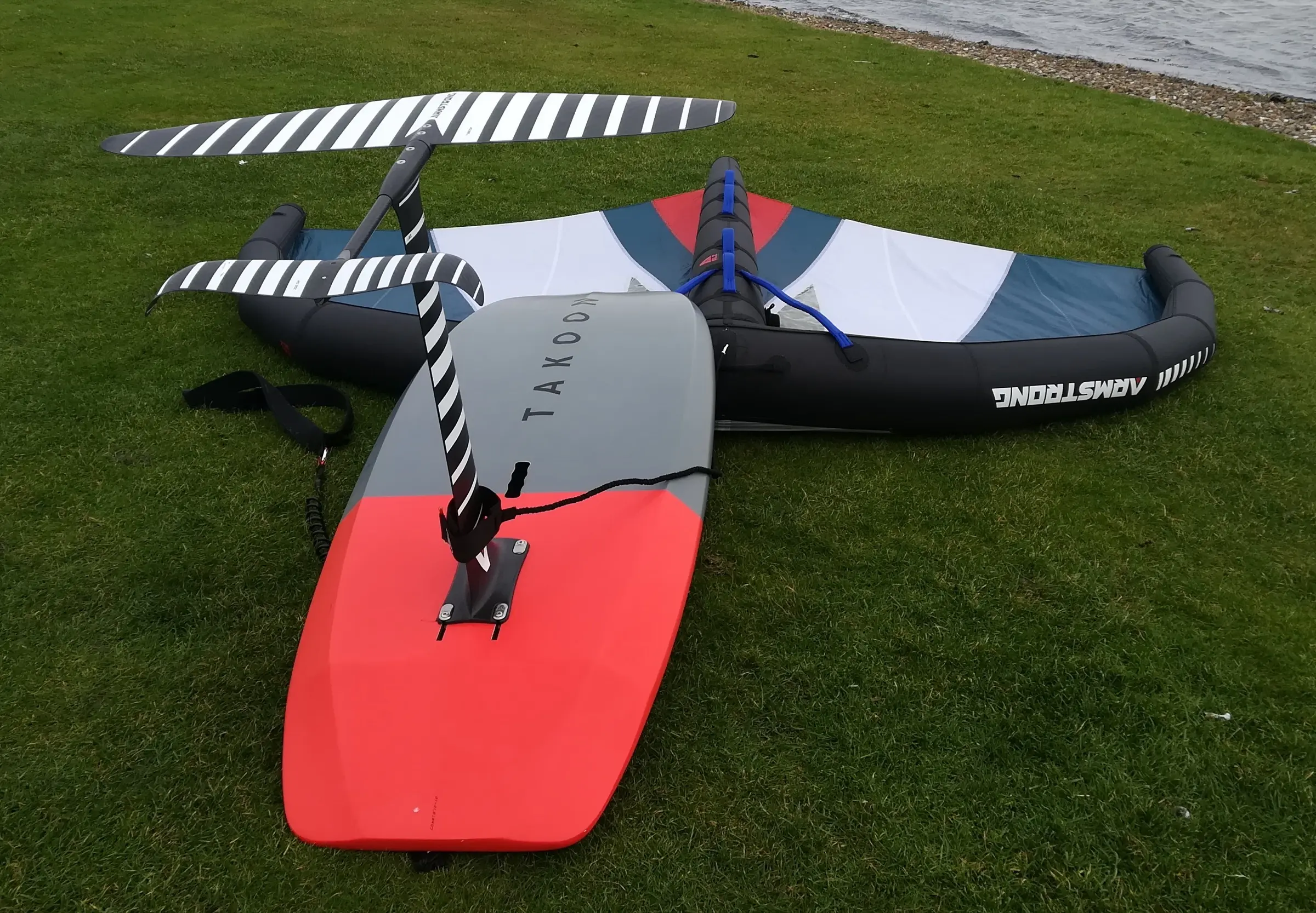 A foil board lying upside down on the shore with its hydrofoil